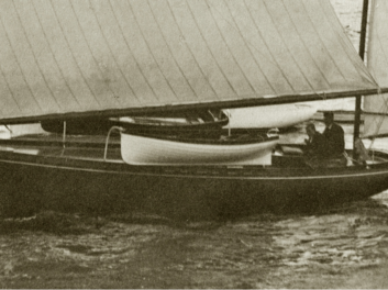 Closeup black and white photo of CONSUELO undersail. Two people are visible aboard.